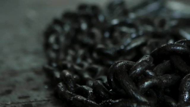 Close up for a pile of black, metal chains lying on the floor for work in the industry. Chains made of iron lying on the floor at the workshop.