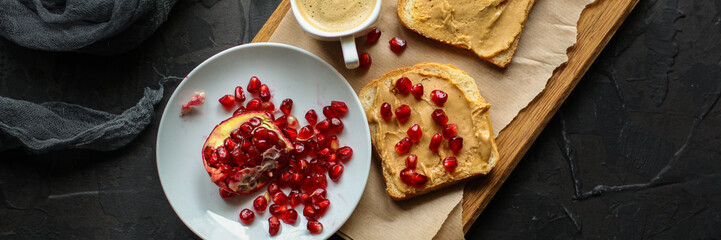 Sandwich with peanut paste and pomegranate grain red - breakfast or sweet snack (dessert). Top view. copy space