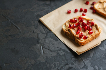 Sandwich with peanut paste and pomegranate grain red - breakfast or sweet snack (dessert). Top view. copy space