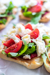 Mini pizza bites as appetizers, puff pastry as a base, topped with tomato puree, mozzarella and fresh ruccola.