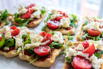 Mini pizza bites as appetizers, puff pastry as a base, topped with tomato puree, mozzarella and fresh ruccola.
