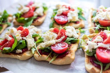 Mini pizza bites as appetizers, puff pastry as a base, topped with tomato puree, mozzarella and fresh ruccola.