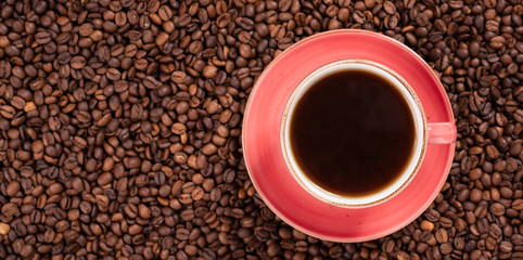 Coffee in a pink cup over coffee beans 