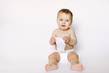 Charming happy little baby girl in white diaper holding wet wipe in her hands and sitting isolated...