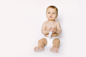 Charming happy little baby girl in white diaper holding wet wipe in her hands and sitting isolated...