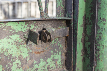 Rusty iron door. The lock on the gate in the country house. Old shabby green paint on the gate. Closed lock on the gate. Vacation home. Protection from robbery.
