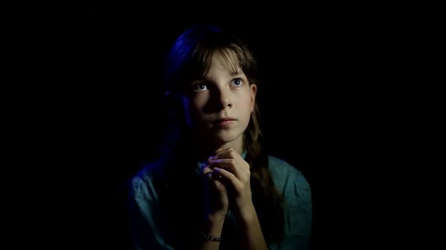 little Orthodox girl praying in a dark room