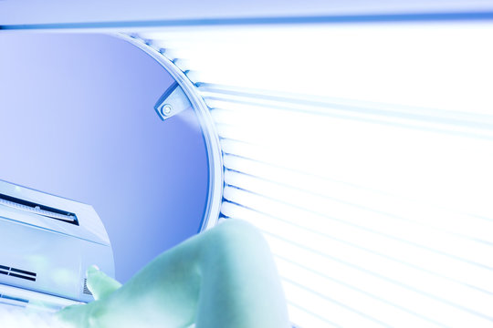 Woman having tan in solarium, female legs, no face