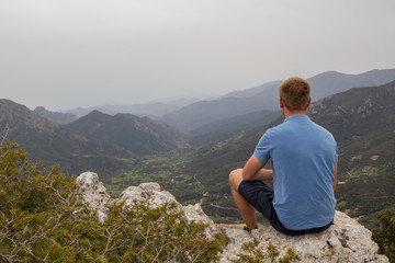 Naklejka premium Person auf einem Felsen, Blick über die Berge