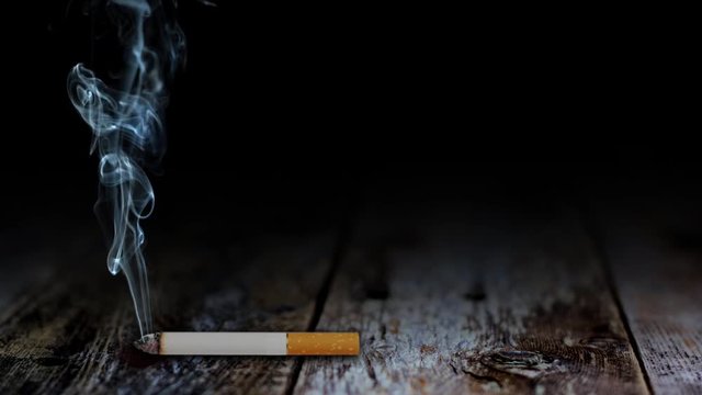 Smoke of Death Table Top features a cigarette lying on a rustic wooden table top with smoke slowly rising from the tip of the cigarette