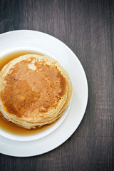 Maple syrup on gold tasty pancakes, top view