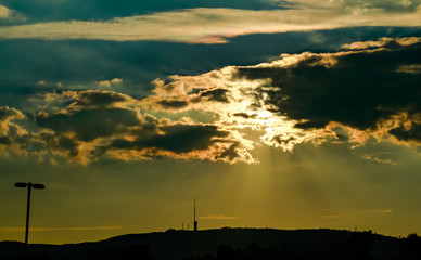 Fototapeta premium Halos de luz solar al atardecer penetrando entre densas nubes sobre el cielo