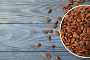 Bowl with pine nuts and space for text on wooden background, top view