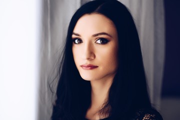 Beauty brunette woman posing near window