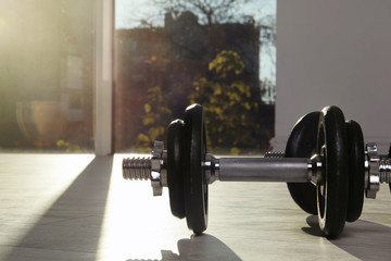 Pair of adjustable dumbbells on floor indoors. Space for text