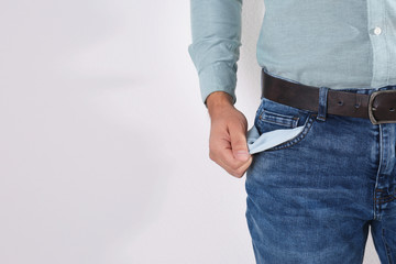Man showing empty pocket on light background, closeup. Space for text