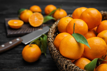 Fresh ripe tangerines in wicker basket on table