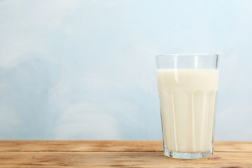 Glass with fresh milk on table against color background. Space for text