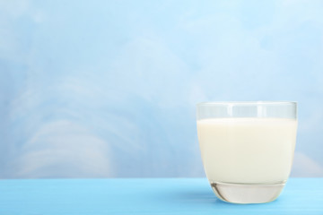 Glass with fresh milk on table against color background. Space for text
