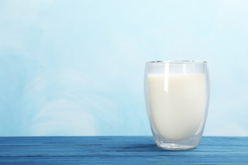 Glass with fresh milk on table against color background. Space for text