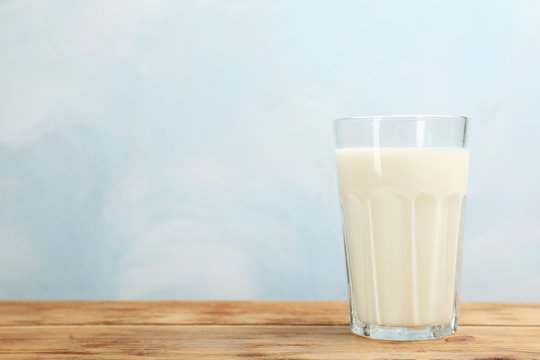 Glass with fresh milk on table against color background. Space for text