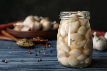Preserved garlic in glass jar on wooden table. Space for text © New Africa