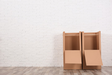 Empty cardboard wardrobe boxes against brick wall indoors. Space for text