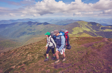 two young people walking down the trail path on mountain. Young couple hiking with backpacks.