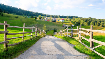 Fototapeta na wymiar Wooden Fence and Countryside Road in Bosaca Village on Durmitor Mountain in Montenegro