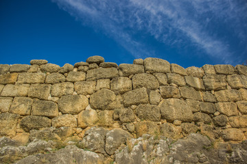 ancient stone wall background texture on rock from below and horizontal border with vivid blue sky, wallpaper pattern copy space