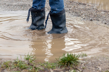 Mann läuft mit Gummistiefel in einer Pfütze
