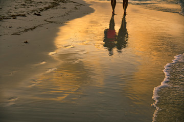 Fototapeta na wymiar sunset on the beach and couple reflection