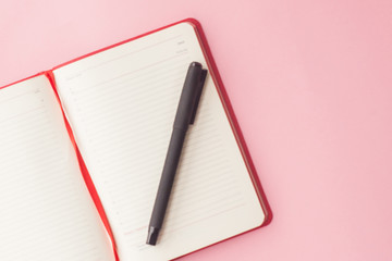 open diary with a pen on a pink background. top view. selective focus. business concept.
