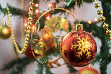 Closeup of red bauble hanging from a decorated Christmas tree