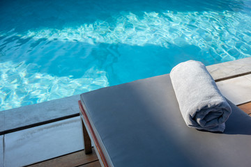 Towel on relaxing pool bed beside swimming pool.