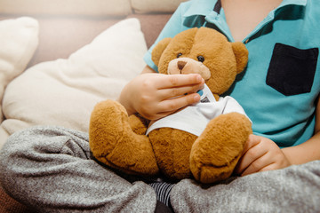 Boy measures the temperature with a thermometer on his teddy bear. Medical and health concept. Taking care of your children's health. Viral disease in a child, treatment and prevention of disease.