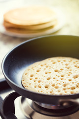 Making american pancakes on frying pan in kitchen interior