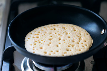 Making american pancakes on frying pan in kitchen interior, closeup