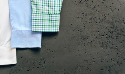 Cuffs from business shirts on a dark background. Vertical sleeves from shirts in green, blue and white. The concept of fashion and sale of luxury clothes.