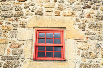 Fototapeta na wymiar Red guillotine window on a stone framed window