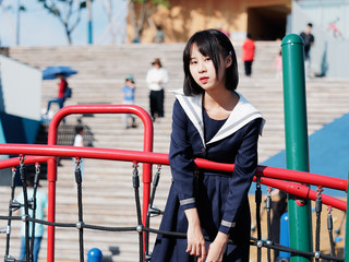Outdoor portrait of beautiful young Chinese girl in blue school uniform japanese style posing in...