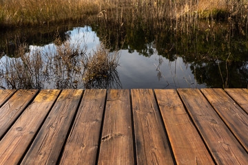 Tables of a wet wooden bridge over a lake.