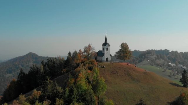 AERIAL: Flying around a beautiful medieval Christian church standing on a hill in fall.