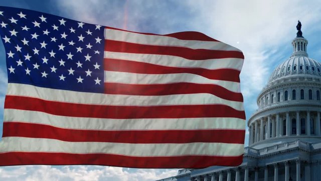 American Flag in Front of Capital Building 4K features an American flag waving in the wind with the Capitol building and moving clouds in the background with a bit of the sun coming through the flag.