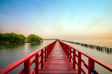 Fototapeta premium Długi czerwony most światło słoneczne niebo drzewo na plaży morze, czerwony most Samut Sakhon Tajlandia