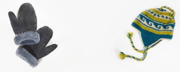 Winter accessories. Mittens made of sheepskin and woolen hat for winter trips on white.