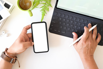 Top view man holding blank screen mobile smartphone on office white desk