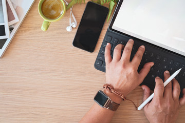 Top view male hand typing smart keyboard  tablet on studio workplace