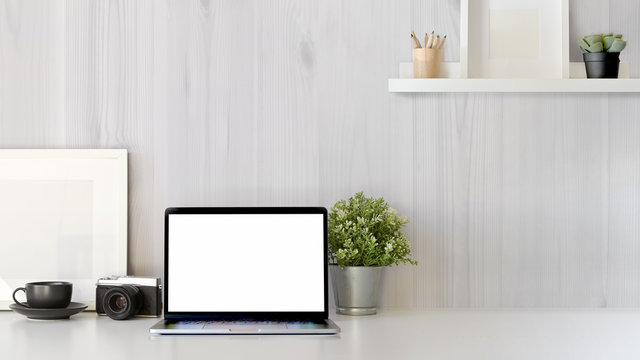 Office desk scenery with mockup blank screen laptop computer. Workspace minimal