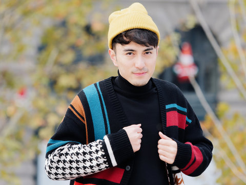 Portrait Of A Handsome Young Man With Colorful Woolen Sweater And Yellow Hat Smiling And Looking At Camera Confidently, Winter Fashion, Cool Young Man Lifestyle.